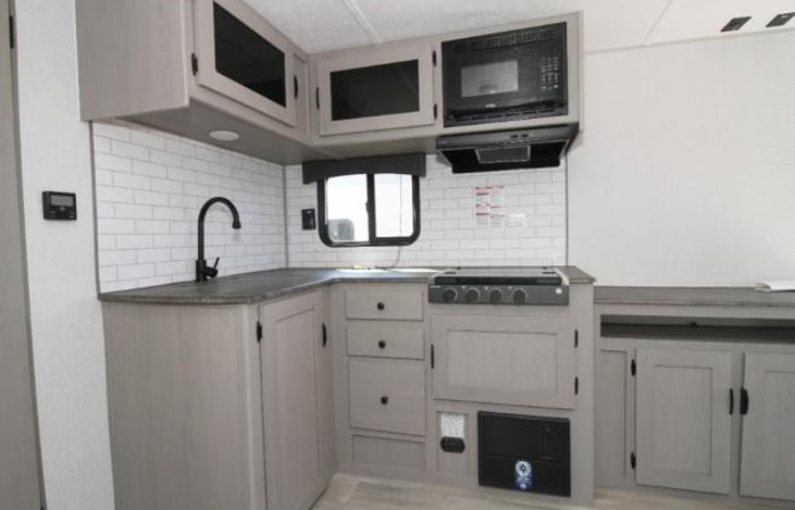 Kitchen with microwave, 3 burner stove and sink.
