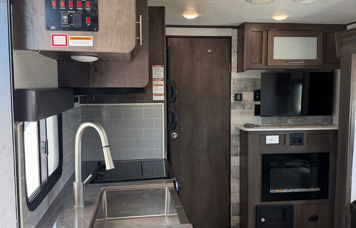 Efficient kitchen area equipped with a deep sink, high-rise faucet, and ample cabinet space.