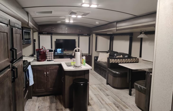 Flat screen TV is visible for all areas of the living and kitchen spaces that provides room to move for all.