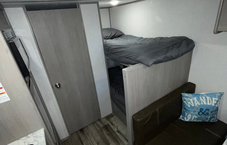 The rear end of the RV Camper. Bunk beds, fridge, microwave, restroom.