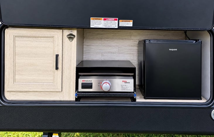 Outdoor kitchen with mini fridge, storage and flat-top griddle — perfect for cooking and dining outside.