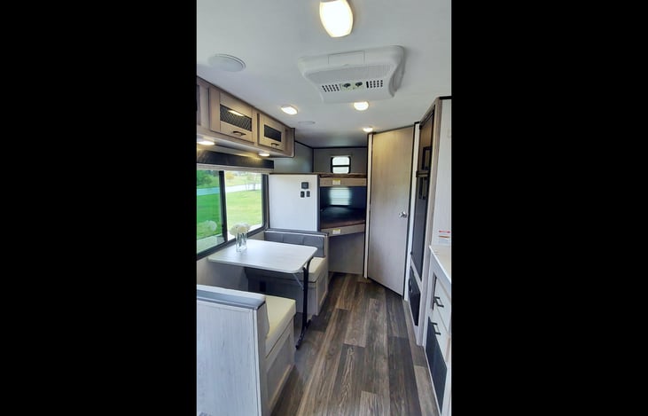 AC/Heat controls at ceiling, LG operable window w/ screen, storage above window & below one bench seat, kitchen table folds into small child bed, 2 LG bunks (200lb capacity ea) w storage niche, outlet