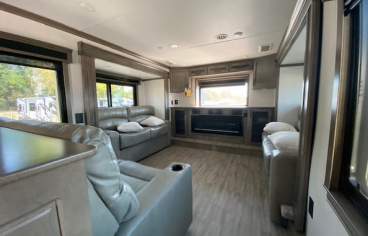 Living room w 65" smart TV & DVD, its own air conditioning. 2 leather couches fold out into comfortable queen beds. RV can sleep up to 8 with younger children sleeping 3/queen +1 on the loveseat.