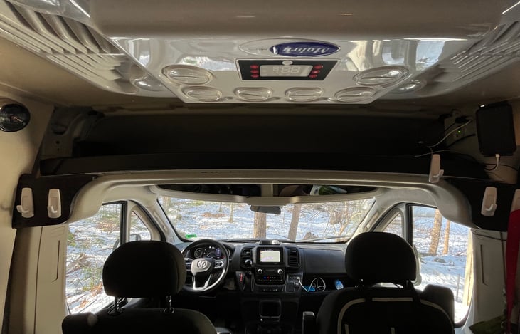 Air conditioner runs on 12 V, use anytime. it right behind the Driver and Passenger front seats.