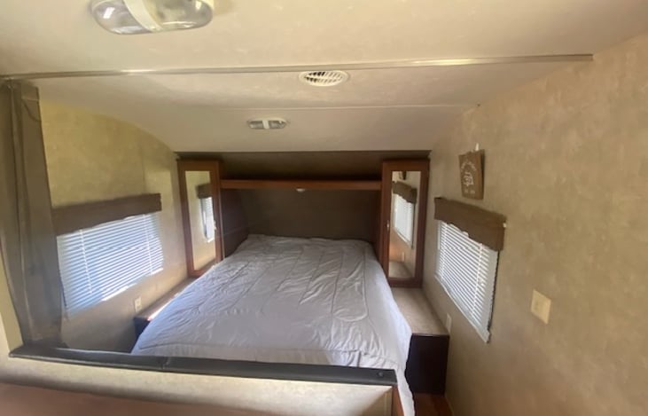 RV Queen sized bed upfront, closets beside, and pull across curtain