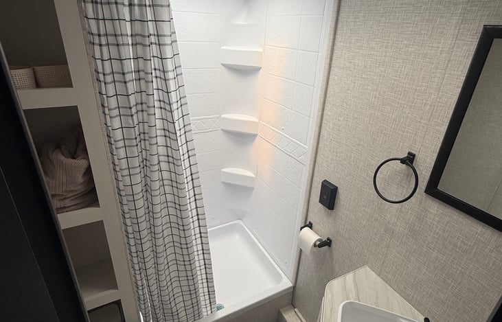Full shower, bathroom mirror, shelves for towels, personal items