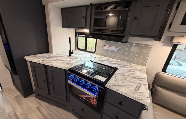 Very large kitchen counter top, double deep large sink, microwave and air fryer over and 3 cook stove top. Very large storage areas here.