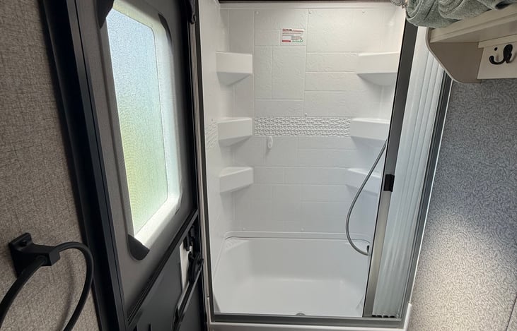 Bathroom shower and toilet. Separate entrance leading to the bathroom from the outside. Shower curtain closes fully so water doesn't get all over the floor like a standard curtain. Stocked w/ towels