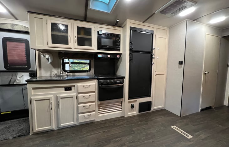 Kitchen area with microwave, stove, vent, freezer, fridge and pantry storage.