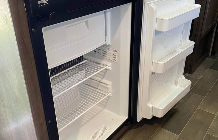 Compact fridge with freezer compartment, runs on propane or shore power.