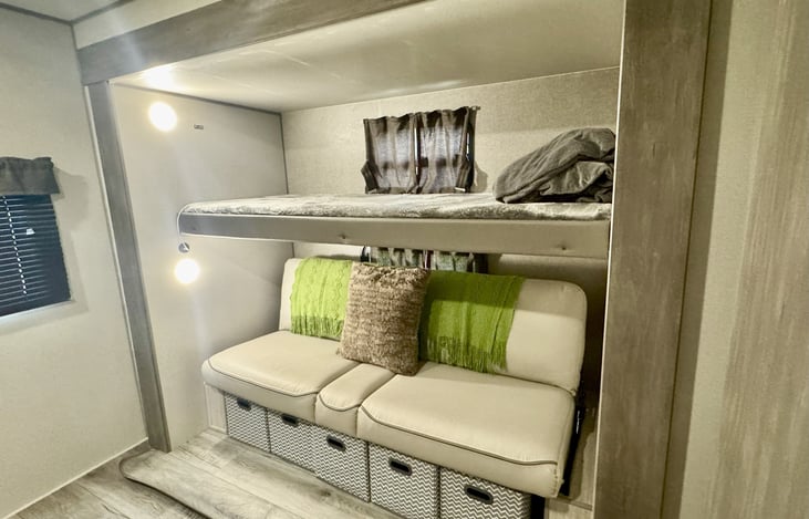 Back bunk folded up into the couch, both with pillows and blankets.