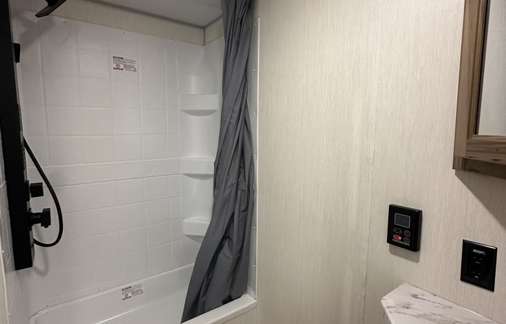 Bathroom shower and vanity area with wall controls visible.