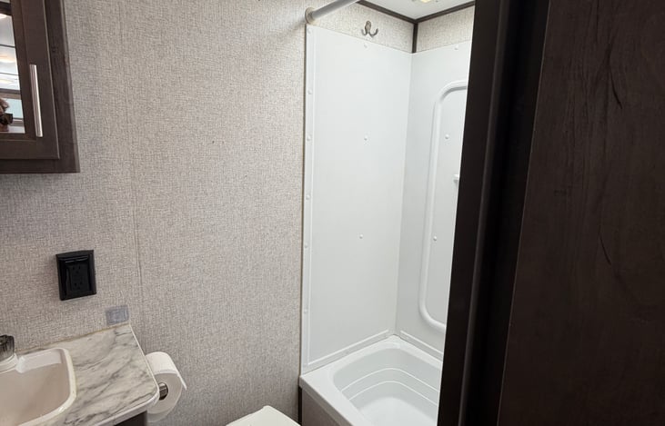 Full indoor shower and tub combo with integrated wall shelving for your toiletries.