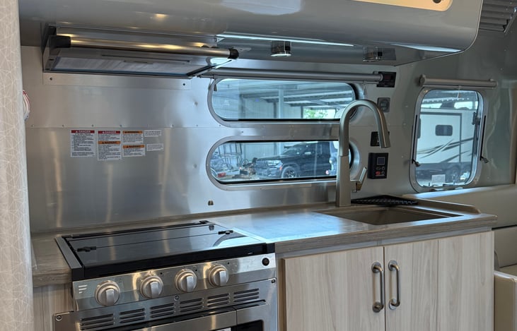 The kitchen includes a sink, stove, convection microwave, and refrigerator. A K-cup coffee maker (not pictured) is in the trailer for morning coffee or afternoon tea.