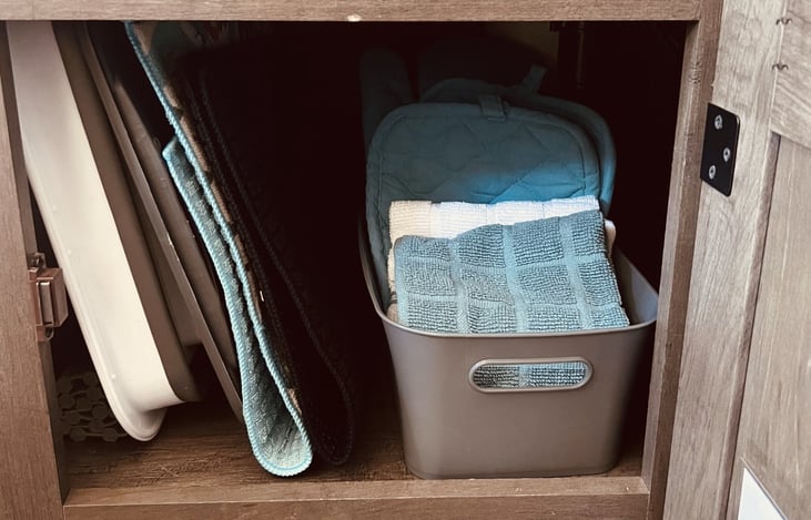 under the kitchen sink you will find drying mats, ovenmits, potholder, and kitchen towels