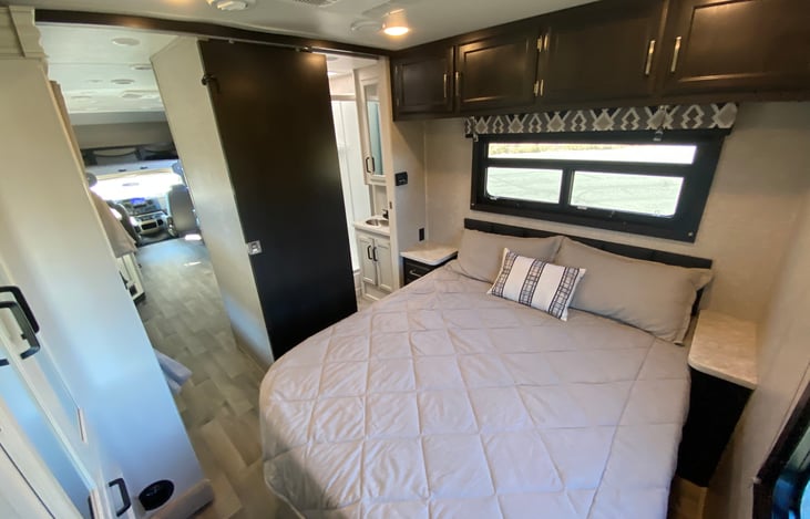 Master bedroom has a queen bed, storage above bed, access to restroom with two pocket doors for privacy