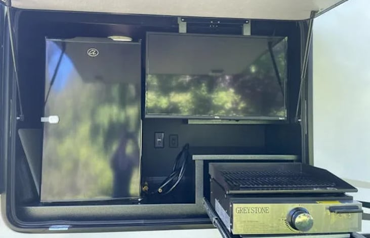 Outdoor kitchen with slide down smart tv.