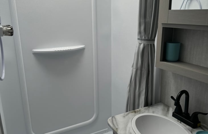 Fully equipped bathroom with toilet, sink, shower, and lots of storage