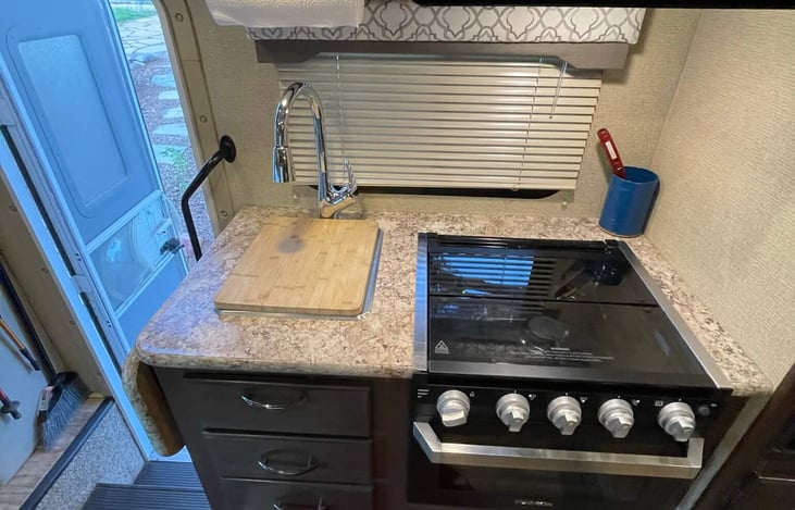 three burner gas stove, oven, microwave oven and sink