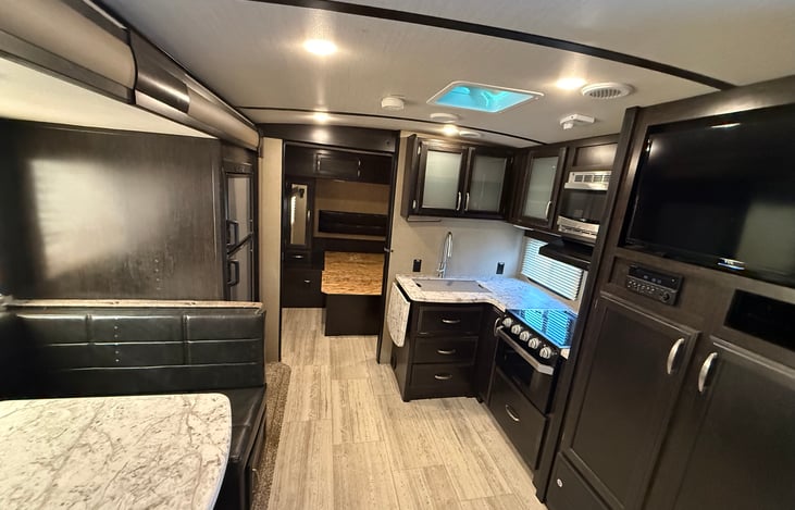 tv and kitchen with view of queen bedroom in front of trailer