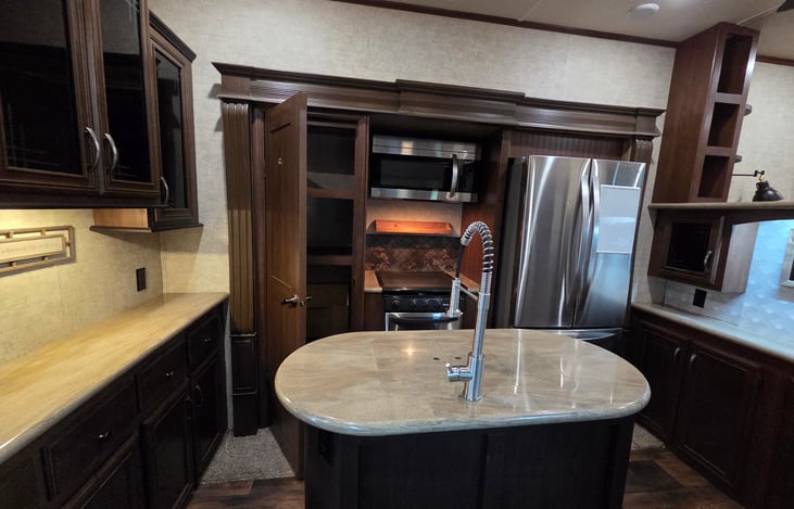 Full kitchen with stovetop/oven, large pantry and full-size refrigerator for groceries.
