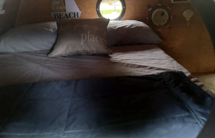 View of the upper bunk, full-sized bed from the port-hole.