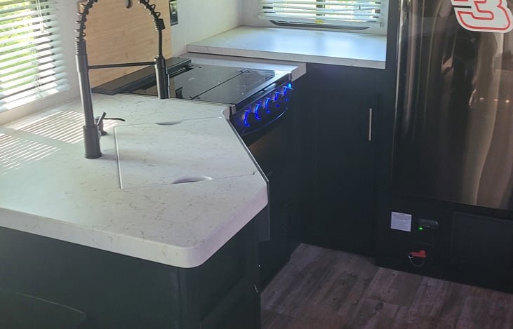 Kitchen has a LOT of counter space for a camper. Farm-style faucet and single-tub sink make cleaning dishes very easy.