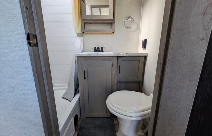 Clean bathroom with extra storage and shower.