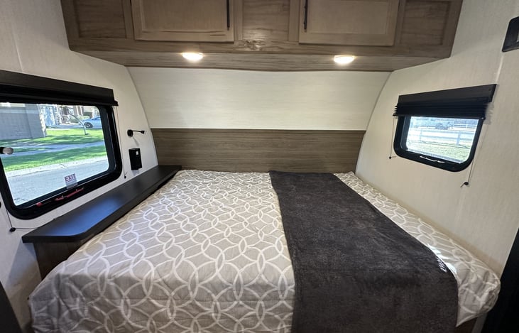 Queen bed area with side windows and overhead storage cabinets.