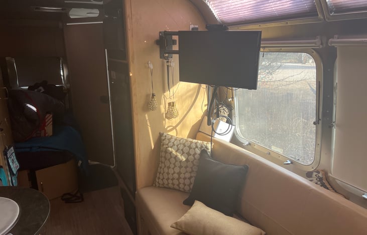 Interior Photo of couch that converts to bed, TV and walkway to Master bed (with upgraded mattress) and fully functional bathroom with shower and privacy divider to separate back bedroom.