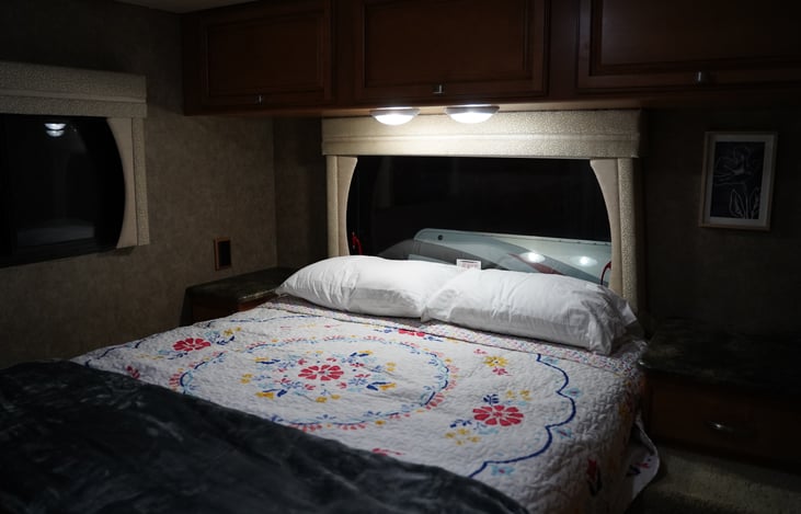 Master Queen Bed. Cabinets located above and nightstands located on each side.