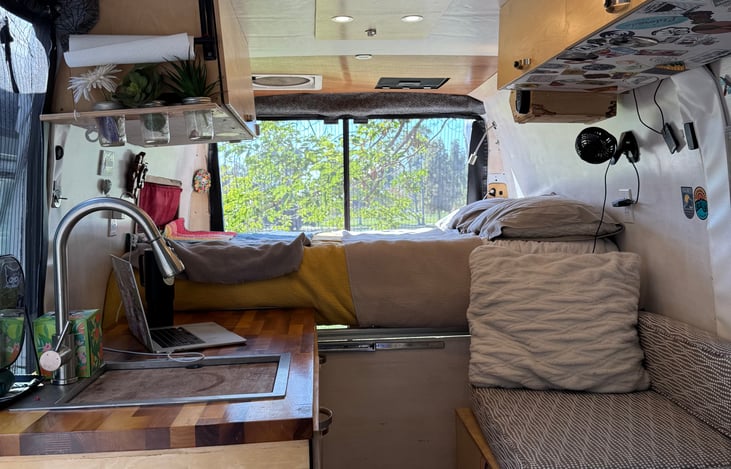 Interior of van view from cab to back of van showing kitchen area, bench, and bed.