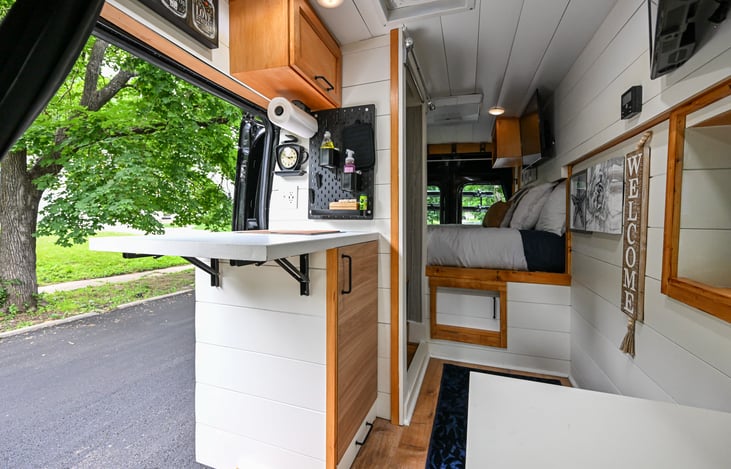 This van features two TVs, a cozy bed, a fully equipped kitchenette, and stylish touches that make your road trip feel like a boutique getaway on the go.