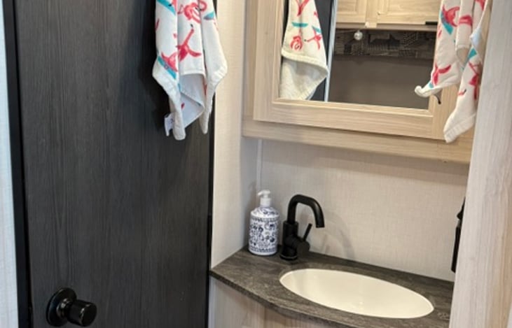 Bathroom sink with medicine cabinet. Stocked with soap and towels.