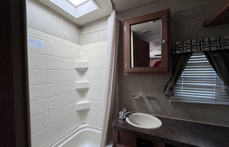 Bathtub with shower. Toilet and vanity. Roomy comfort just like home