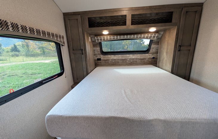 Cozy front bedroom featuring an upgraded residential mattress for a great night's sleep, TV, and bright windows with a massive automotive panoramic front view!