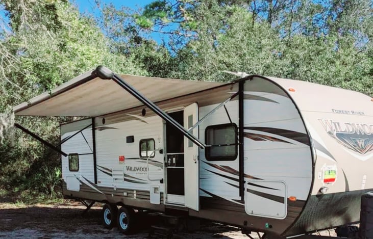 Exterior front of camper with power awning out. Set up your mat, chairs, and turn on the outside speakers for music. LED lights under the awning for nighttime fun.