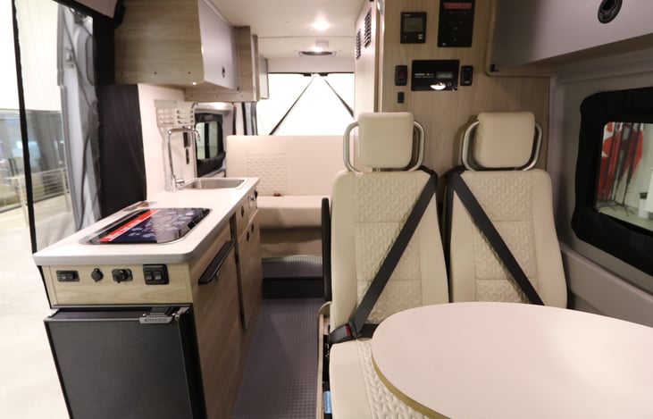 2 automotive seat belts behind the cab seats. Cab seats swivel around to create a dining area. The cab seats, plus the 4 coach seats provide 6 total 3 point seat belts
