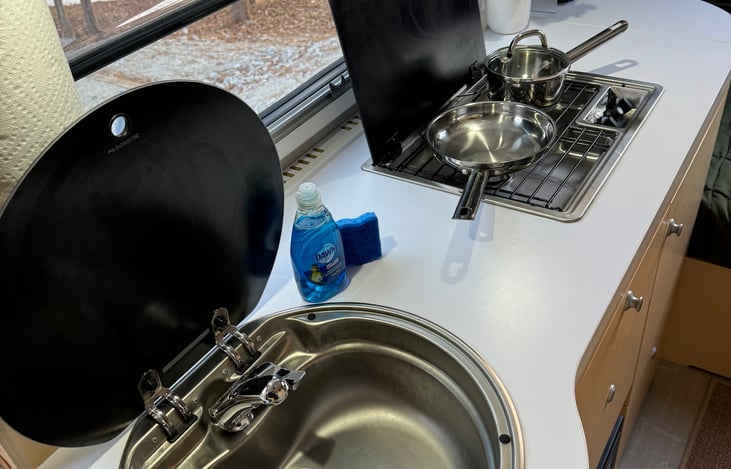 Deep sink with faucet with hot and cold water. Lid can be closed to maximize counter space.