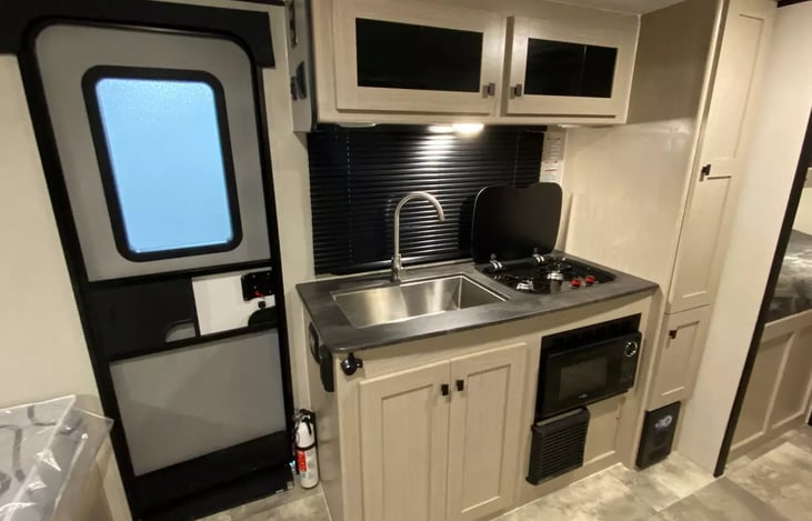 Kitchen galley with flush 2 burner cooktop, microwave, farm style sink and cabinetry