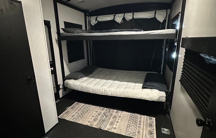 Bunk beds in the rear of the camper. The bathroom is on the left and there is a door separating the back from the kitchen.