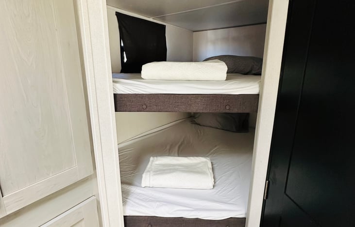 Full over full bunk beds with bedding and pillows.