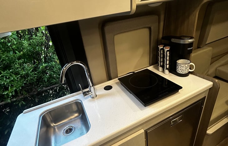 Sink, wireless phone charger, electric cooktop, microwave, refrigerator with built in freezer. Includes cookware, utensils, plates, trash bags, paper towels, cleanings supplies, & disposable gloves.
