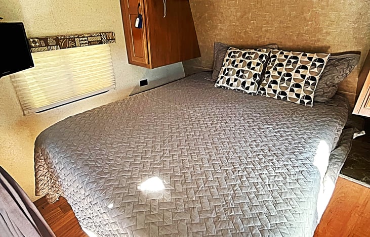 queen sized bed in separate sleeping area with small tv