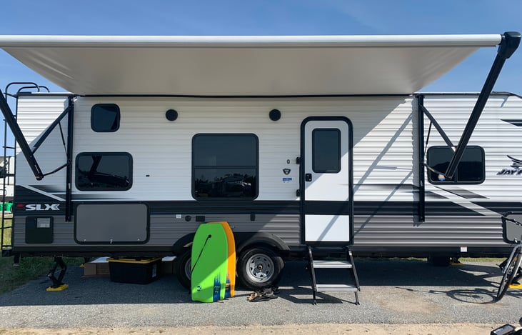 Side View showing camper with outdoor speakers, outlet, propane hookup, tv hookups, storage compartments.