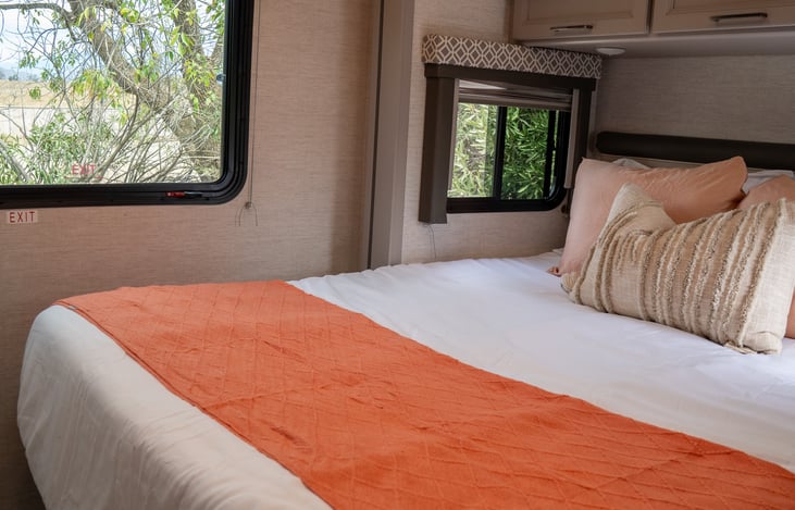 queen sized bed with room to walk around and overhead storage