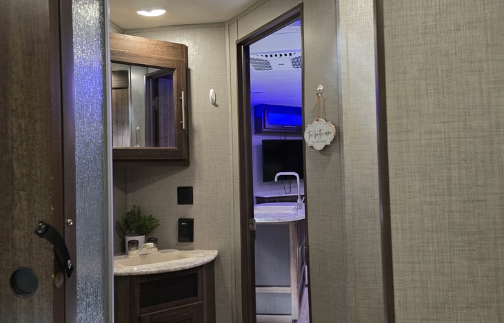 View from primary bedroom into main living area with full bath in between