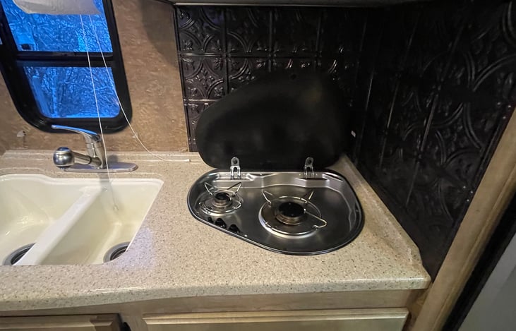 Two small propane burners and divided sink for doing dishes.