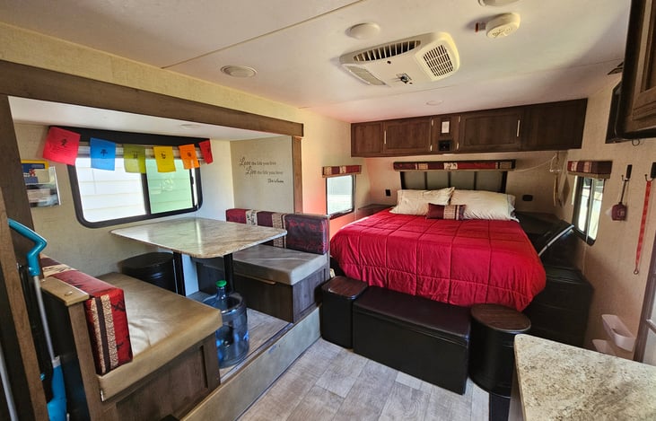 Short Queen bed includes linens and pillows, also showing additional storage ottoman and storage seating