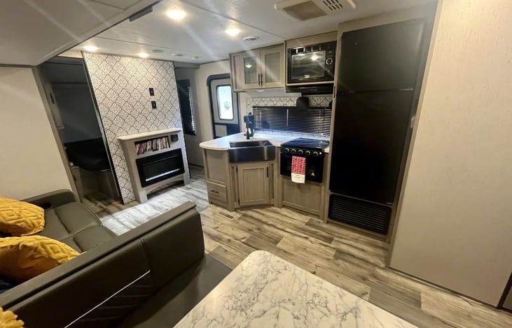 Kitchen/living room area. Shown full fridge, 3 burner stovetop, oven, microwave and FarmStyle sink.